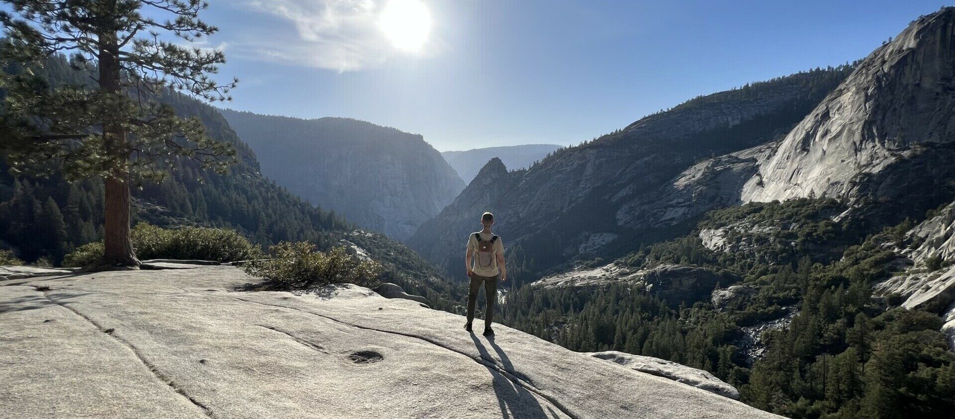 Person standing on the edge of a cliff looking down at Yosemite Valley